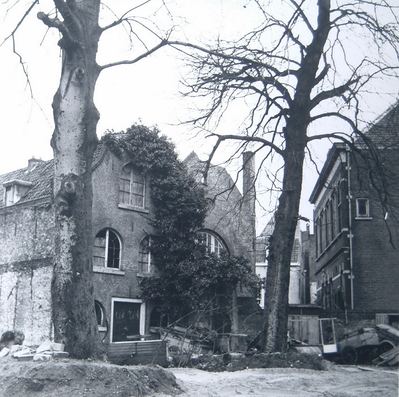 Achterzijde van de ruïneuze synagoge (midden) aan de Varkenmarkt met rechts de bijbehorende school. Links staat een pakhuis.